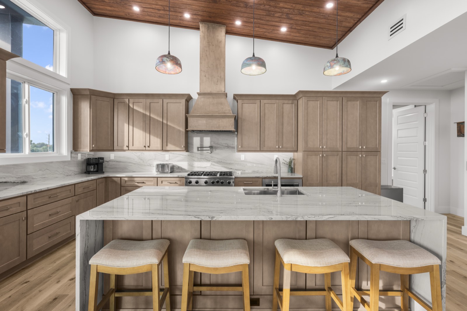 Kitchen with marble waterfall island and wood plank ceiling