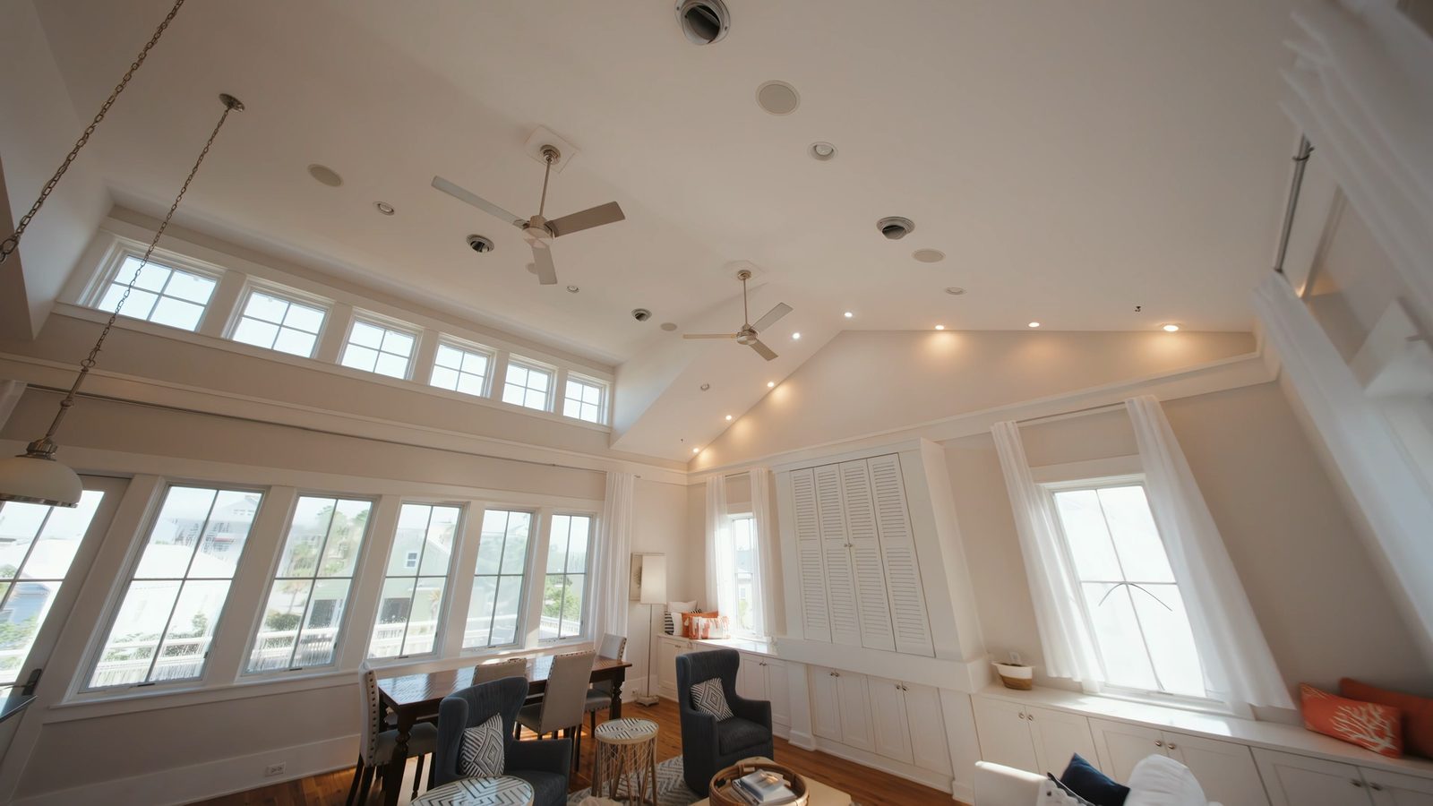 FPV frame mid-pass through a bright living room, camera tilted toward the clerestory windows